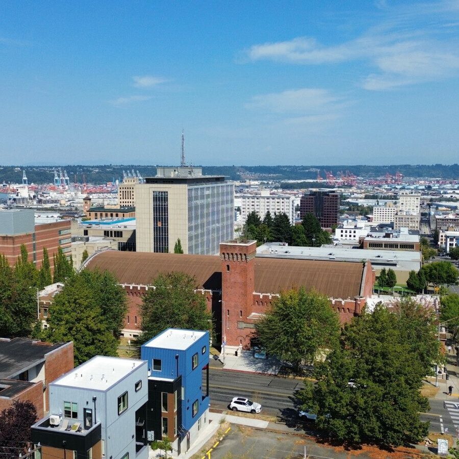 Aerial view of a cityscape featuring modern and historic buildings, bustling streets, and a harbor under a clear blue sky—showcasing the vibrancy ideal for South Sound commercial property management services.